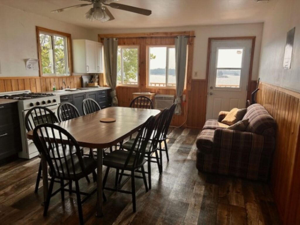 Picture of a kitchen, dining room table and a sofa in a rental cabin at Separation Lake Lodge with the lake showing through the windows and door