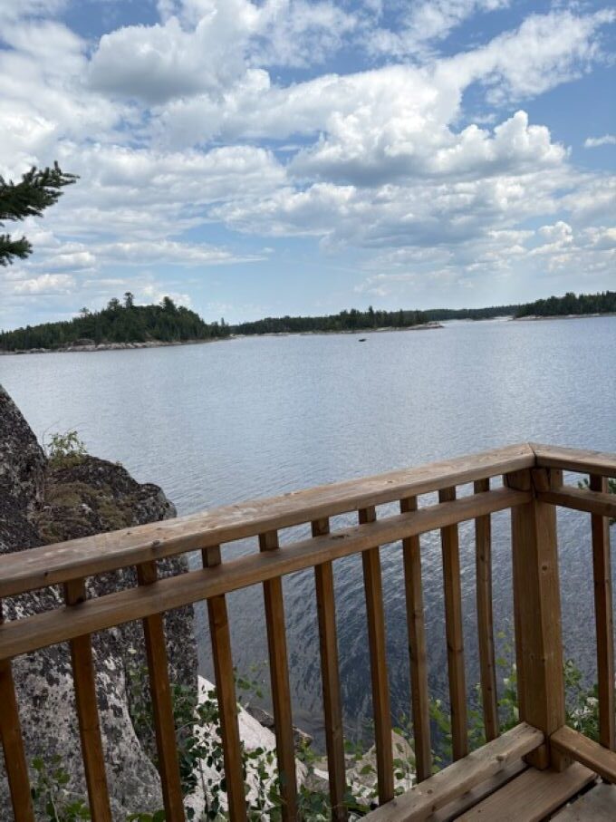 Lakeview from cabin deck with rocks, trees and lake